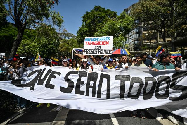 University students, opponents of the government, and relatives of political prisoners, take part in a march on the Youth Day with signs reading "The can be no transition with political prisoners" and "May them all be included" in Caracas on February 12, 2026. The first major opposition demonstration after the fall of Nicolas Maduro during a US military incursion a month ago gathered thousands of people in Venezuelas capital on February 12, ahead of the approval of a historic amnesty law. (Photo by Juan BARRETO / AFP)
