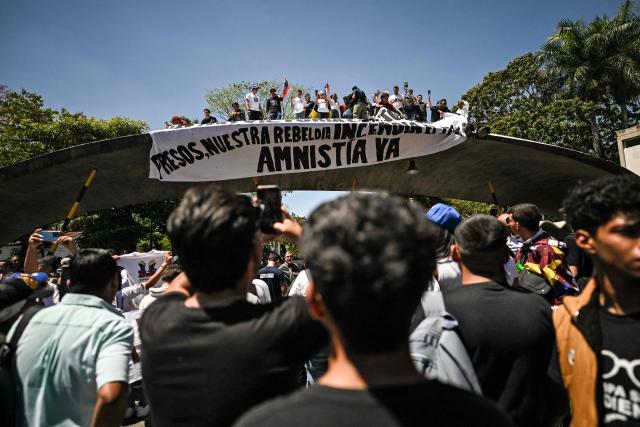 University students, opponents of the government, and relatives of political prisoners, take part in a march on the Youth Day with a sign reading "Prisoners, our rebellion burns. Amnesty now" in Caracas on February 12, 2026. The first major opposition demonstration after the fall of Nicolas Maduro during a US military incursion a month ago gathered thousands of people in Venezuelas capital on February 12, ahead of the approval of a historic amnesty law. (Photo by Juan BARRETO / AFP)