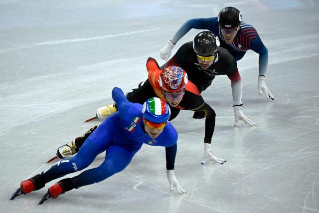 (L-R) Italy's Pietro Sighel, China's Sun Long, Latvia's Roberts Kruzbergs and France's Quentin Fercoq compete in the short track speed skating men's 1000m quarter-final during the Milano Cortina 2026 Winter Olympic Games at Milano Ice Skating Arena in Milan on February 12, 2026. (Photo by WANG Zhao / AFP)
