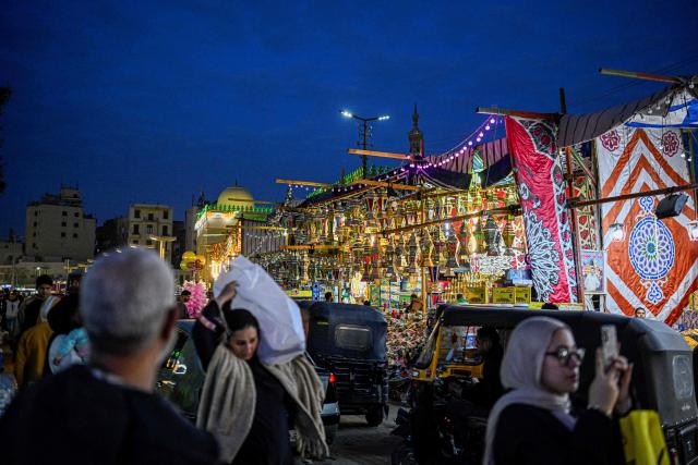 People walk past a shop displaying traditional lanterns, a popular decorative item used during the month of Ramadan, at a market in Sayyida Zeinab district in the old quarters of Cairo on February 12, 2026, as people prepare to welcome the Muslim fasting week. (Photo by Khaled DESOUKI / AFP)