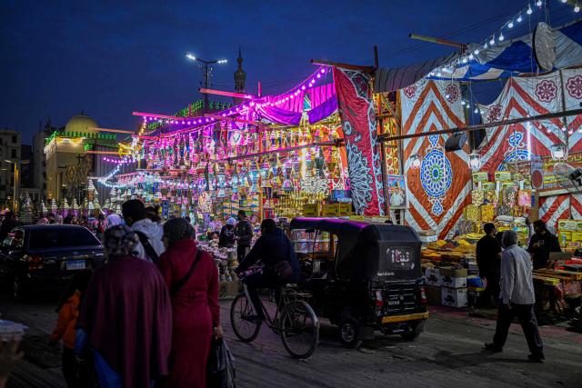 People walk past a shop displaying traditional lanterns, a popular decorative item used during the month of Ramadan, at a market in Sayyida Zeinab district in the old quarters of Cairo on February 12, 2026, as people prepare to welcome the Muslim fasting week. (Photo by Khaled DESOUKI / AFP)