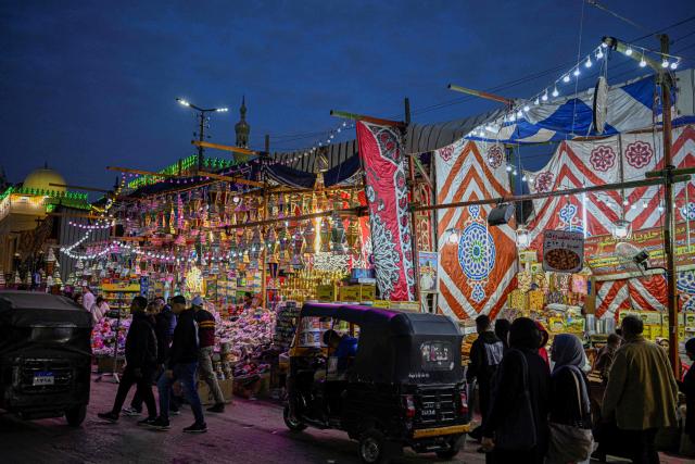 People walk past a shop displaying traditional lanterns, a popular decorative item used during the month of Ramadan, at a market in Sayyida Zeinab district in the old quarters of Cairo on February 12, 2026, as people prepare to welcome the Muslim fasting week. (Photo by Khaled DESOUKI / AFP)