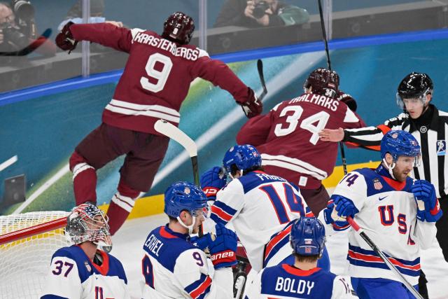 Latvia's #09 Renars Krastenbergs (L) celebratres scoring the 1-1 goal past USA's #37 Connor Hellebuyck during the men's preliminary round Group C Ice Hockey match between Latvia and USA at the Milano Santagiulia Ice Hockey Arena during the Milano Cortina 2026 Winter Olympic Games in Milan, on February 12, 2026. (Photo by Alexander NEMENOV / AFP)