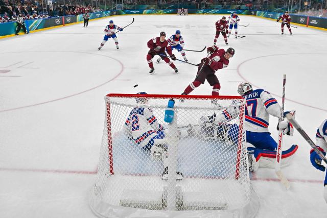 Latvia's #11 Dans Locmelis (C) shoots but fails to score past USA's #37 Connor Hellebuyck during the men's preliminary round Group C Ice Hockey match between Latvia and USA at the Milano Santagiulia Ice Hockey Arena during the Milano Cortina 2026 Winter Olympic Games in Milan, on February 12, 2026. (Photo by Alexander NEMENOV / POOL / AFP)