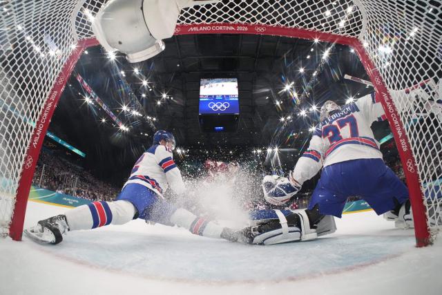 USA's #12 Matt Boldy (L) and USA's #37 Connor Hellebuyck block a shot during the men's preliminary round Group C Ice Hockey match between Latvia and USA at the Milano Santagiulia Ice Hockey Arena during the Milano Cortina 2026 Winter Olympic Games in Milan, on February 12, 2026. (Photo by POOL / AFP)