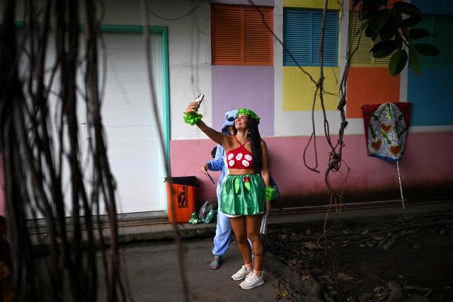Revellers take a selfie during the parade of the Loucura Suburbana (Suburban Craziness) street carnival group at the Engenho de Dentro neighborhood in Rio de Janeiro, Brazil on February 12, 2026. (Photo by Mauro PIMENTEL / AFP)