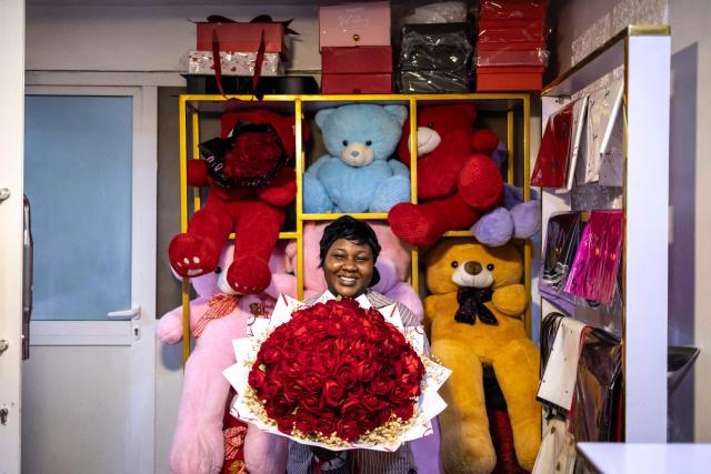 Anu Sholola, 24, an admin officer at the Surprise World NG gift shop, poses for a photograph with a flower bouquet at the Surprise World NG office in Ikeja in Lagos, on February 10, 2026. (Photo by OLYMPIA DE MAISMONT / AFP)