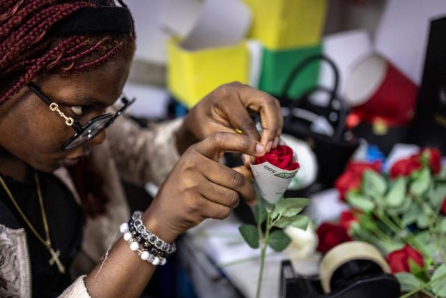 A Surprise World NG employee circles a flower with a 500 naira note at the Surprise World NG office in Ikeja in Lagos, on February 10, 2026. (Photo by OLYMPIA DE MAISMONT / AFP)