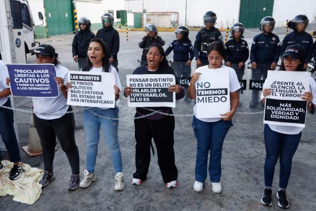 Relatives of political prisoners hold signs as they take part in a protest outside the Bolivarian National Police (PNB) Zone 7 prison in Caracas on February 12, 2026. Venezuela's legislature on February 12 postponed the adoption of a landmark amnesty bill expected to lead to the release of hundreds of political prisoners. (Photo by Pedro MATTEY / AFP)