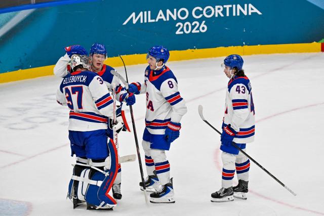 USA's #37 Connor Hellebuyck (L) celebrates with teammates USA's #07 Brady Tkachuk, USA's #08 Zach Werenski and USA's #43 Quinn Hughes after winning their men's preliminary round Group C Ice Hockey match between Latvia and USA at the Milano Santagiulia Ice Hockey Arena during the Milano Cortina 2026 Winter Olympic Games in Milan, on February 12, 2026. (Photo by Alexander NEMENOV / AFP)