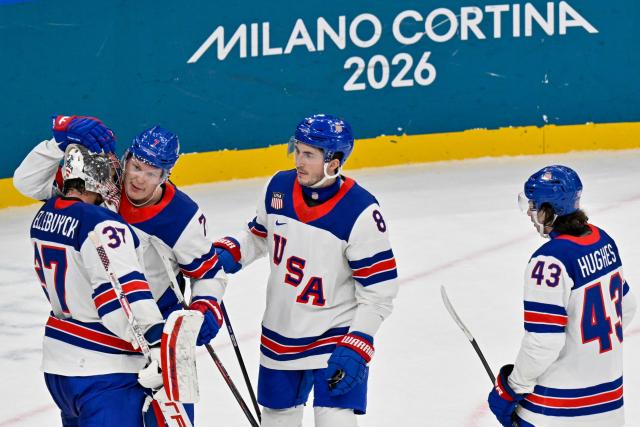 USA's #37 Connor Hellebuyck (L) celebrates with teammates USA's #07 Brady Tkachuk, USA's #08 Zach Werenski and USA's #43 Quinn Hughes after winning their men's preliminary round Group C Ice Hockey match between Latvia and USA at the Milano Santagiulia Ice Hockey Arena during the Milano Cortina 2026 Winter Olympic Games in Milan, on February 12, 2026. (Photo by Alexander NEMENOV / AFP)