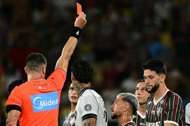 Referee Rafael Rodrigo Klein shows a red card to Fluminense's Uruguayan midfielder #17 Agustin Canobbio (2nd-R) during the Campeonato Brasileiro Serie A football match between Fluminense and Botafogo at the Maracana Stadium in Rio de Janeiro, Brazil, on February 12, 2026. (Photo by Pablo PORCIUNCULA / AFP)