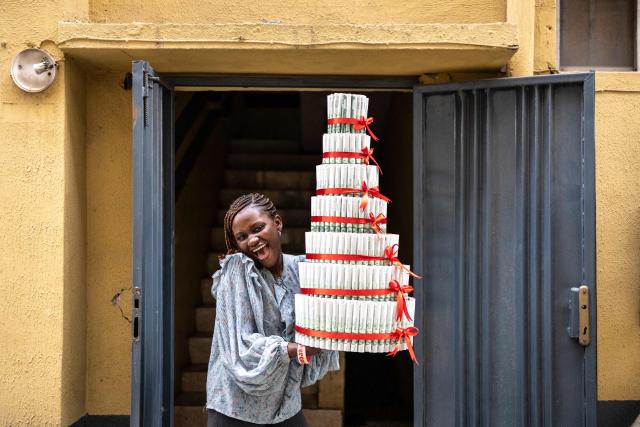 Rachael Kelani, 23, a content creator at the Surprise World NG gift shop, poses for a photograph with a money tower at the Surprise World NG office in Ikeja in Lagos, on February 10, 2026. (Photo by OLYMPIA DE MAISMONT / AFP)