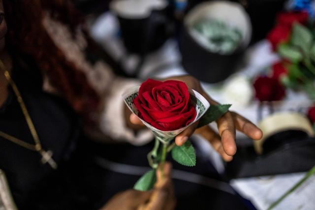 A Surprise World NG employee circles a flower with a 500 naira note at the Surprise World NG office in Ikeja in Lagos, on February 10, 2026. (Photo by OLYMPIA DE MAISMONT / AFP)