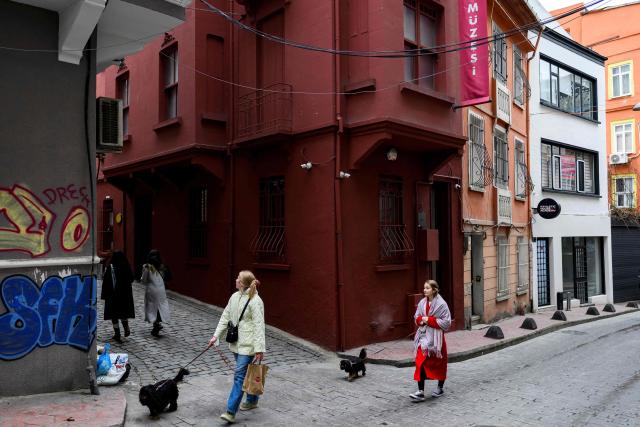 Pedestrians walk past The Museum of Innocence in Istanbul on February 10, 2026. On a cobbled street in Cukurcuma, a district known for its antiques shops on Istanbul's European side, the story penned by Nobel Literature Prize-winning Turkish author Orhan Pamuk has been brought to life inside the walls of a red-painted house. (Photo by Yasin AKGUL / AFP)