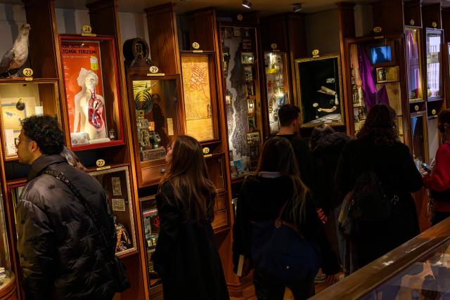 Visitors look at The display cases in The Museum of Innocence in Istanbul on February 10, 2026. On a cobbled street in Cukurcuma, a district known for its antiques shops on Istanbul's European side, the story penned by Nobel Literature Prize-winning Turkish author Orhan Pamuk has been brought to life inside the walls of a red-painted house. (Photo by Yasin AKGUL / AFP)