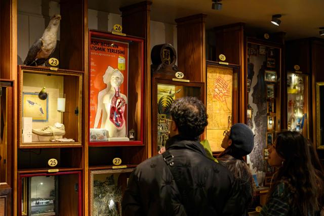 Visitors look at the display cases in the Museum of Innocence in Istanbul on February 10, 2026. On a cobbled street in Cukurcuma, a district known for its antiques shops on Istanbul's European side, the story penned by Nobel Literature Prize-winning Turkish author Orhan Pamuk has been brought to life inside the walls of a red-painted house. (Photo by Yasin AKGUL / AFP)