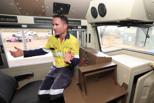 A member of staff delivers a briefing about a newly unveiled battery-electric locomotive by Fortescue Metals Group in Port Hedland, Western Australia on February 12, 2026. Fortescue has officially started phasing out the diesel trains that transport iron ore from its mines to port in a move that the mining group hopes will save about one million litres of diesel a year. Fortescue is aiming for its iron ore mining and transportion to emit zero carbon emissions by the end of 2030. (Photo by Antony DICKSON / AFP)