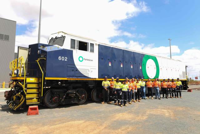 Staff members pose with a newly unveiled battery-electric locomotive by Fortescue Metals Group in Port Hedland, Western Australia on February 12, 2026. Fortescue has officially started phasing out the diesel trains that transport iron ore from its mines to port in a move that the mining group hopes will save about one million litres of diesel a year. Fortescue is aiming for its iron ore mining and transportion to emit zero carbon emissions by the end of 2030. (Photo by Antony DICKSON / AFP)