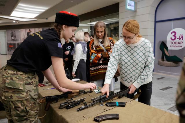 Attendees learn how to disassemble and reassemble a Kalashnikov rifle model during a demonstration event organized by members of the "Berkut Military-Sports Cossack Club" in a shopping centre in Voronezh on January 24, 2026. (Photo by TATYANA MAKEYEVA / AFP)
