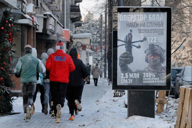 Runners pass a poster advertising contract military service in the Russian army's unmanned systems units in Voronezh on January 24, 2026. (Photo by TATYANA MAKEYEVA / AFP)