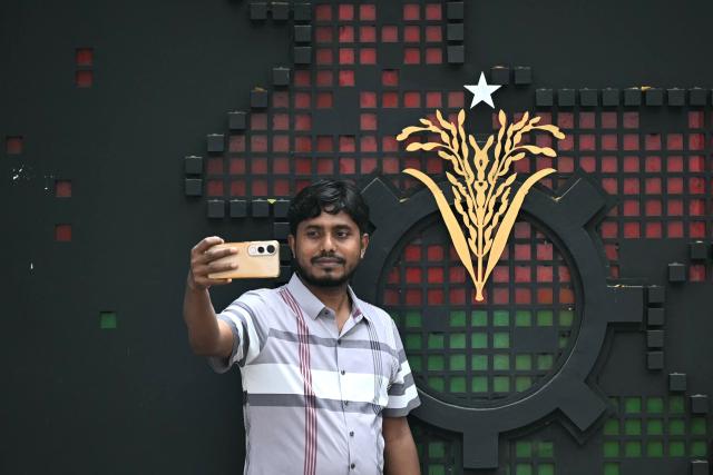 A man takes a selfie outside the office of Bangladesh Nationalist Party (BNP) chairman Tarique Rahman, in Dhaka on February 13, 2026. BNP claimed a thumping win on February 13 in the first elections held since a deadly 2024 uprising, with leader Tarique Rahman poised to become prime minister. (Photo by Sajjad HUSSAIN / AFP)