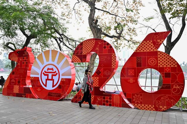 A woman walks past a 2026 sign at Hoan Kiem Lake ahead of the Lunar New Year in Hanoi on February 13, 2026. (Photo by Nhac NGUYEN / AFP)