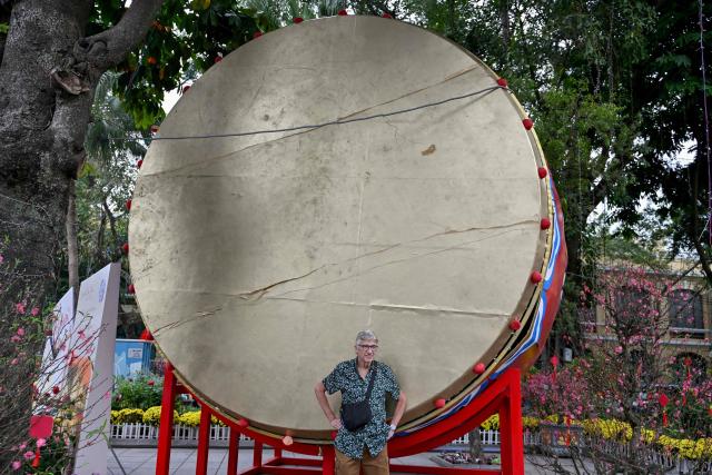 A visitor stands in front of a decorative drum ahead of the Lunar New Year in Hanoi on February 13, 2026. (Photo by Nhac NGUYEN / AFP)