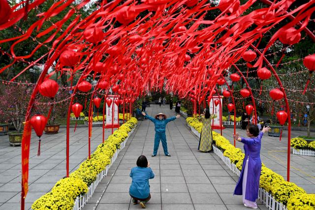 Women pose for photos under lanterns and decorations ahead of the Lunar New Year in Hanoi on February 13, 2026. (Photo by Nhac NGUYEN / AFP)