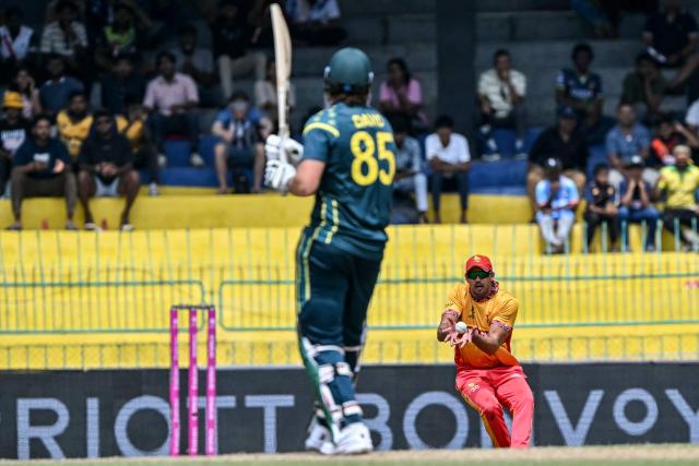 Zimbabwe's Graeme Cremer (R) takes a catch to dismiss Australia's Tim David (L) during the 2026 ICC Men's T20 Cricket World Cup group stage match between Australia and Zimbabwe at the R Premadasa Stadium in Colombo on February 13, 2026. (Photo by Ishara S. KODIKARA / AFP)