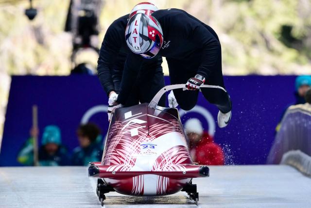 Latvia's Jekabs Kalenda pilots in the bobsleigh men's 2-man training Heat 3 at Cortina Sliding Centre during the Milano Cortina 2026 Winter Olympic Games in Cortina d'Ampezzo on February 13, 2026. (Photo by Stefano RELLANDINI / AFP)