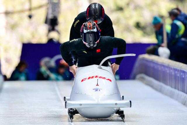 China's Li Chunjian pilots in the bobsleigh men's 2-man training Heat 3 at Cortina Sliding Centre during the Milano Cortina 2026 Winter Olympic Games in Cortina d'Ampezzo on February 13, 2026. (Photo by Stefano RELLANDINI / AFP)