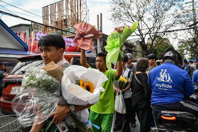People buy flowers at a market ahead of Valentine's Day in Manila on February 13, 2026. (Photo by Jam STA ROSA / AFP)