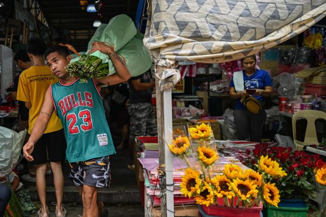 A worker carries flowers at a market ahead of Valentine's Day in Manila on February 13, 2026. (Photo by Jam STA ROSA / AFP)