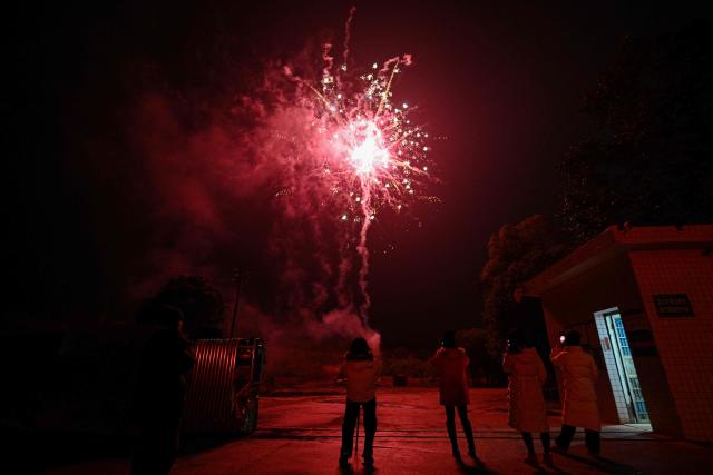 In this photo taken on January 21, 2026, people film the fireworks in Liuyang town, Changsha, central China's Hunan province. A fiery crack of red and gold explodes above a village in southern China's Liuyang, where residents are accustomed to ear-splitting fireworks tests year-round in the country's pyrotechnics production hub. (Photo by Adek BERRY / AFP) / To go with 'CHINA-ECONOMY-FIREWORKS'