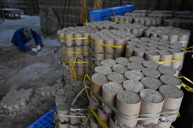In this photo taken on January 21, 2026, a man works at a fireworks factory in Liuyang town, Changsha, central China's Hunan province. A fiery crack of red and gold explodes above a village in southern China's Liuyang, where residents are accustomed to ear-splitting fireworks tests year-round in the country's pyrotechnics production hub. (Photo by Adek BERRY / AFP) / To go with 'CHINA-ECONOMY-FIREWORKS'