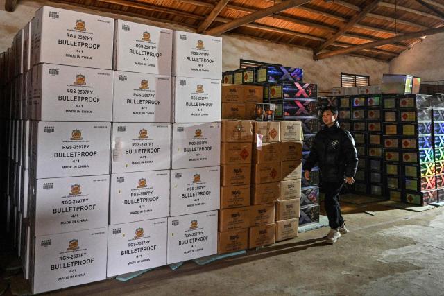 In this photo taken on January 22, 2026, an employee walks inside a warehouse at a fireworks factory in Liuyang town, Changsha, central China's Hunan province. A fiery crack of red and gold explodes above a village in southern China's Liuyang, where residents are accustomed to ear-splitting fireworks tests year-round in the country's pyrotechnics production hub. (Photo by Adek BERRY / AFP) / To go with 'CHINA-ECONOMY-FIREWORKS'