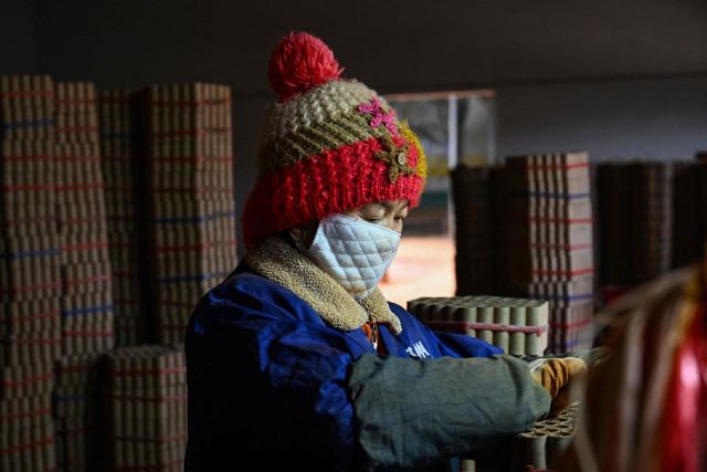 In this photo taken on January 22, 2026, a woman works at a fireworks factory in Liuyang town, Changsha, central China's Hunan province. A fiery crack of red and gold explodes above a village in southern China's Liuyang, where residents are accustomed to ear-splitting fireworks tests year-round in the country's pyrotechnics production hub. (Photo by Adek BERRY / AFP) / To go with 'CHINA-ECONOMY-FIREWORKS'