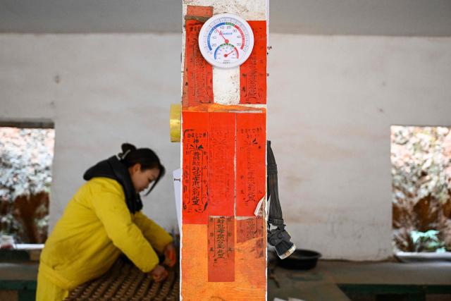 In this photo taken on January 22, 2026, a woman works at a fireworks factory in Liuyang town, Changsha, central China's Hunan province. A fiery crack of red and gold explodes above a village in southern China's Liuyang, where residents are accustomed to ear-splitting fireworks tests year-round in the country's pyrotechnics production hub. (Photo by Adek BERRY / AFP) / To go with 'CHINA-ECONOMY-FIREWORKS'