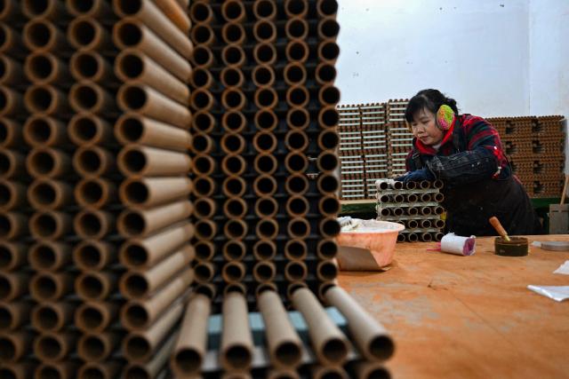 In this photo taken on January 22, 2026, a woman works at a fireworks factory in Liuyang town, Changsha, central China's Hunan province. A fiery crack of red and gold explodes above a village in southern China's Liuyang, where residents are accustomed to ear-splitting fireworks tests year-round in the country's pyrotechnics production hub. (Photo by Adek BERRY / AFP) / To go with 'CHINA-ECONOMY-FIREWORKS'