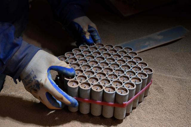 In this photo taken on January 22, 2026, a man works at a fireworks factory in Liuyang town, Changsha, central China's Hunan province. A fiery crack of red and gold explodes above a village in southern China's Liuyang, where residents are accustomed to ear-splitting fireworks tests year-round in the country's pyrotechnics production hub. (Photo by Adek BERRY / AFP) / To go with 'CHINA-ECONOMY-FIREWORKS'