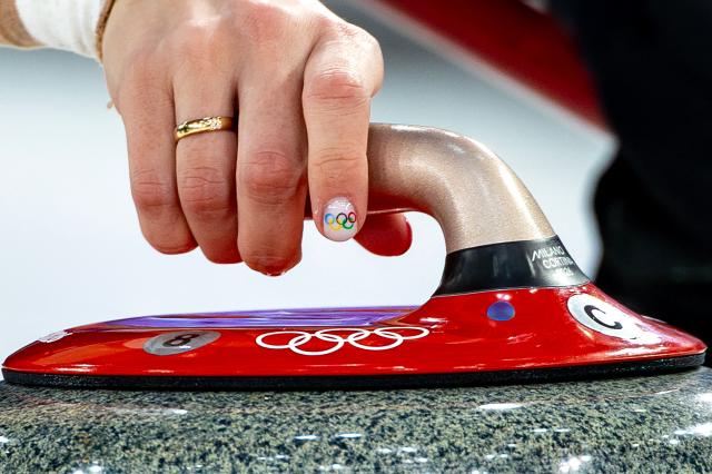 A nail with the Olympic rings logo is seen on the right hand of Denmark's Jasmin Holtermann as she releases the stone during the curling women's round robin between Denmark and Japan during the Milano Cortina 2026 Winter Olympic Games at the Cortina Curling Olympic Stadium in Cortina d’Ampezzo on February 12, 2026. (Photo by Odd ANDERSEN / AFP)
