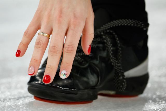 A nail with the Olympic rings logo is seen on the right hand of Denmark's Jasmin Holtermann  during the curling women's round robin between Denmark and Japan during the Milano Cortina 2026 Winter Olympic Games at the Cortina Curling Olympic Stadium in Cortina d’Ampezzo on February 12, 2026. (Photo by Odd ANDERSEN / AFP)