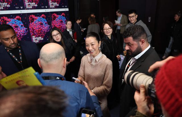 Malaysian actress Michelle Yeoh signs autographs at the end of a press conference, as she was awarded with the Honorary Golden Bear trophy "in recognition of her outstanding achievements in film and cinema" during the Berlinale, Europe's first major film festival of the year, in Berlin on February 13, 2026. (Photo by Ronny HARTMANN / AFP)