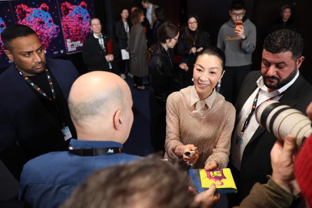 Malaysian actress Michelle Yeoh signs autographs at the end of a press conference, as she was awarded with the Honorary Golden Bear trophy "in recognition of her outstanding achievements in film and cinema" during the Berlinale, Europe's first major film festival of the year, in Berlin on February 13, 2026. (Photo by Ronny HARTMANN / AFP)