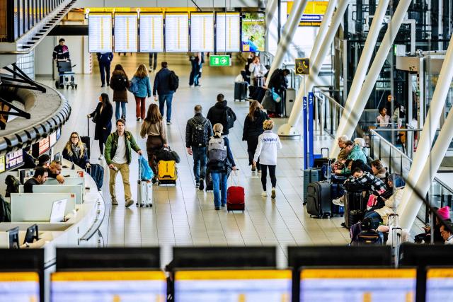 Passengers carrying luggage walk through the Schiphol Airport, ahead of the presentation of the Royal Schiphol Group's annual figures, in Schiphol on February 13, 2026. (Photo by Jeffrey Groeneweg / ANP / AFP) / Netherlands OUT