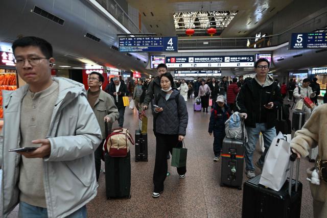 Passengers walk towards gates before boarding their trains at a train station in Beijing on February 13, 2026, as people travel to their hometowns ahead of Lunar New Year celebrations. (Photo by AFP)