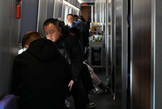 Passengers sit onboard a train in Beijing on February 13, 2026, as people travel to their hometowns ahead of Lunar New Year celebrations. (Photo by AFP)