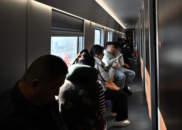 Passengers sit onboard a train in Beijing on February 13, 2026, as people travel to their hometowns ahead of Lunar New Year celebrations. (Photo by AFP)