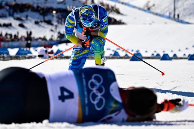 Ukraine's Oleksandr Lisohor (top) reacts after crossing the finish line next to Latvia's Raimo Vigants during the men's 10km cross-country interval start free event of the Milano Cortina 2026 Winter Olympic Games at Tesero Cross-Country Skiing Stadium in Lago di Tesero (Val di Fiemme) on February 13, 2026. (Photo by Tobias SCHWARZ / AFP)